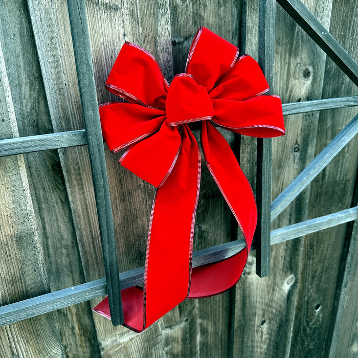 quintessential red velvet Christmas bow on a fence