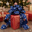 Large gift wrapped in Christmas gift wrap and topped with  a large royal blue velvet bow with white snowflakes